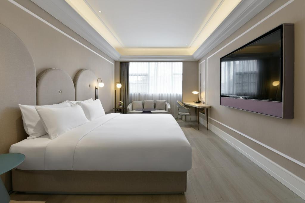 a bedroom with a large white bed and a flat screen tv at Mercure Shenzhen Nanshan in Shenzhen