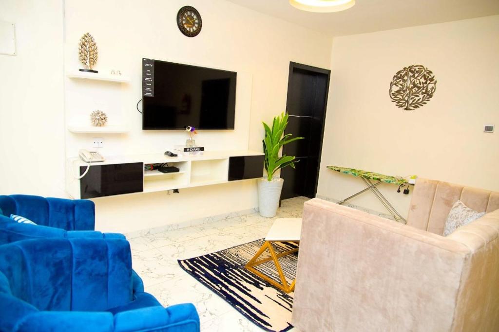 a living room with two blue chairs and a tv at U2 One Bedroom Apartment in Lagos