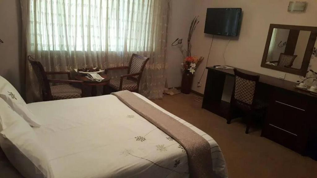 um quarto com uma cama, uma mesa e um espelho em Leopards road room em Lusaka