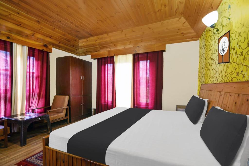 1 dormitorio con 1 cama grande y cortinas rojas en OYO Asha Cottage, en Manali