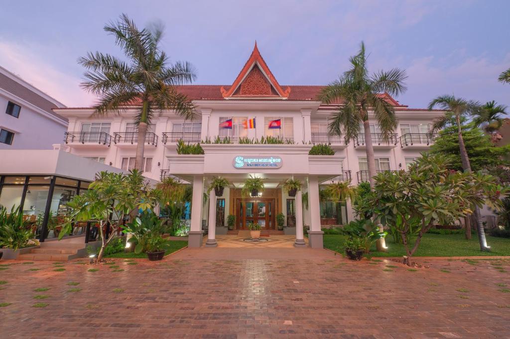 a large white building with palm trees in front of it at Sala Siem Reap Hotel in Siem Reap