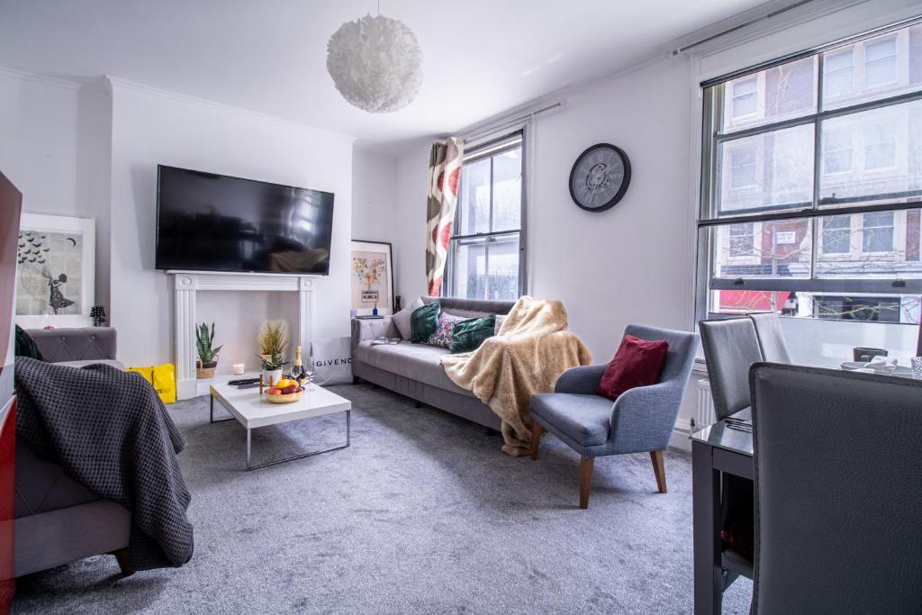 ein Wohnzimmer mit einem Sofa, Stühlen und einem TV in der Unterkunft Seymour Place, Hyde Park, Edgware Road London Apartments in London