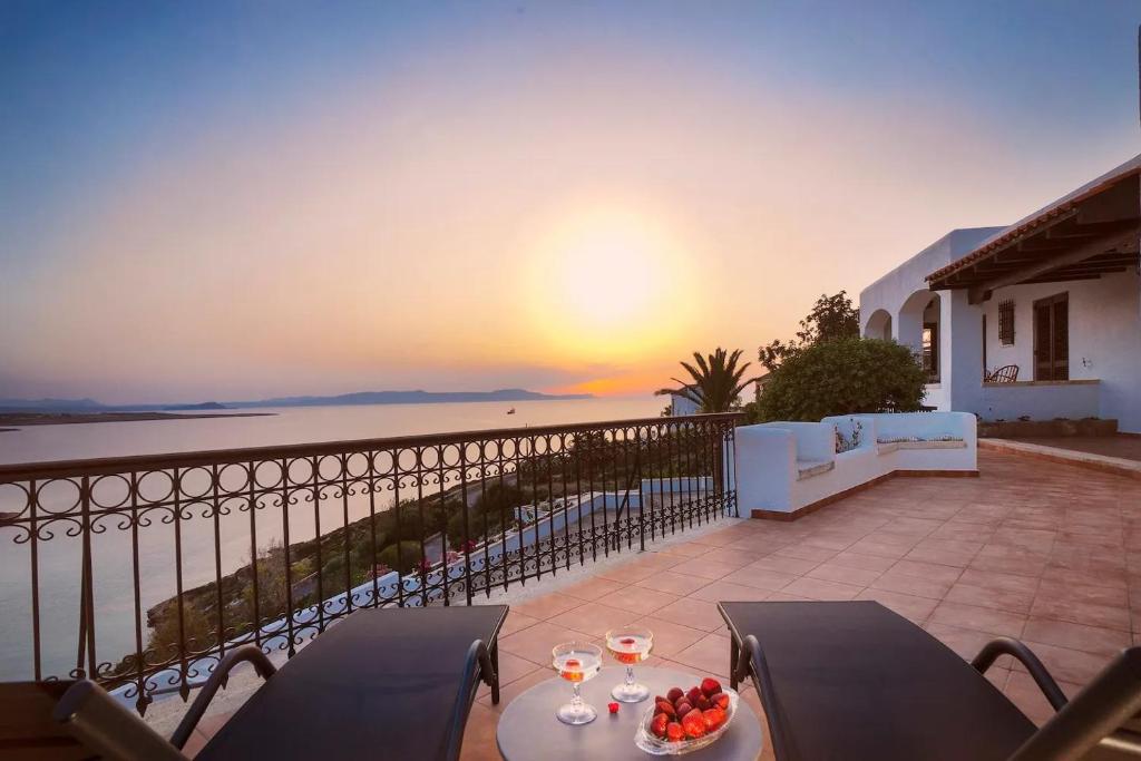 een balkon met een tafel met wijnglazen en een zonsondergang bij Casa Bella Vista in Kalathas