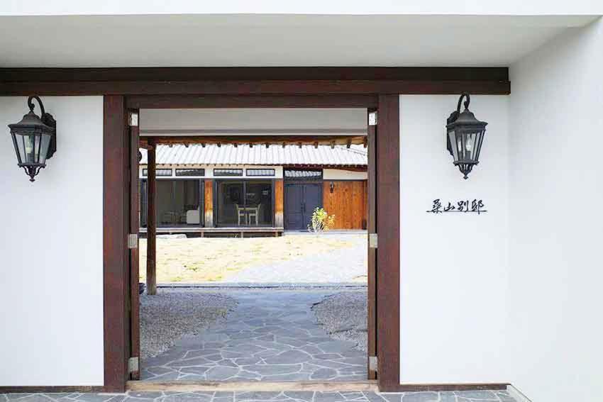 an entrance to a building with two lights on the wall at Kuwayama Bettei in Mitoyo