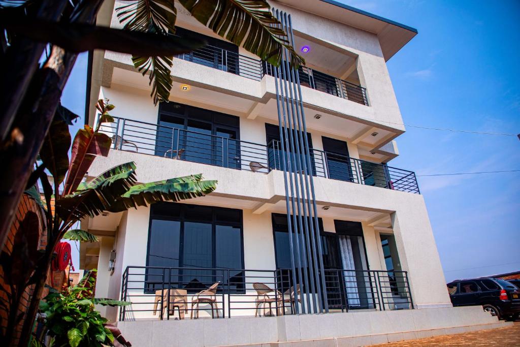 un edificio con balcones y mesas delante de él en The Vacation Homes Apartments en Kigali