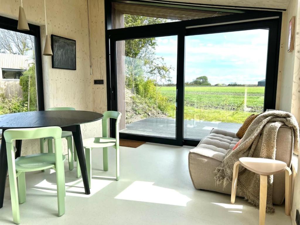 ein Wohnzimmer mit einem Tisch, Stühlen und einem Sofa in der Unterkunft Hello Zeeland - Tiny House Zeeuwse Liefde 5 in Westkapelle