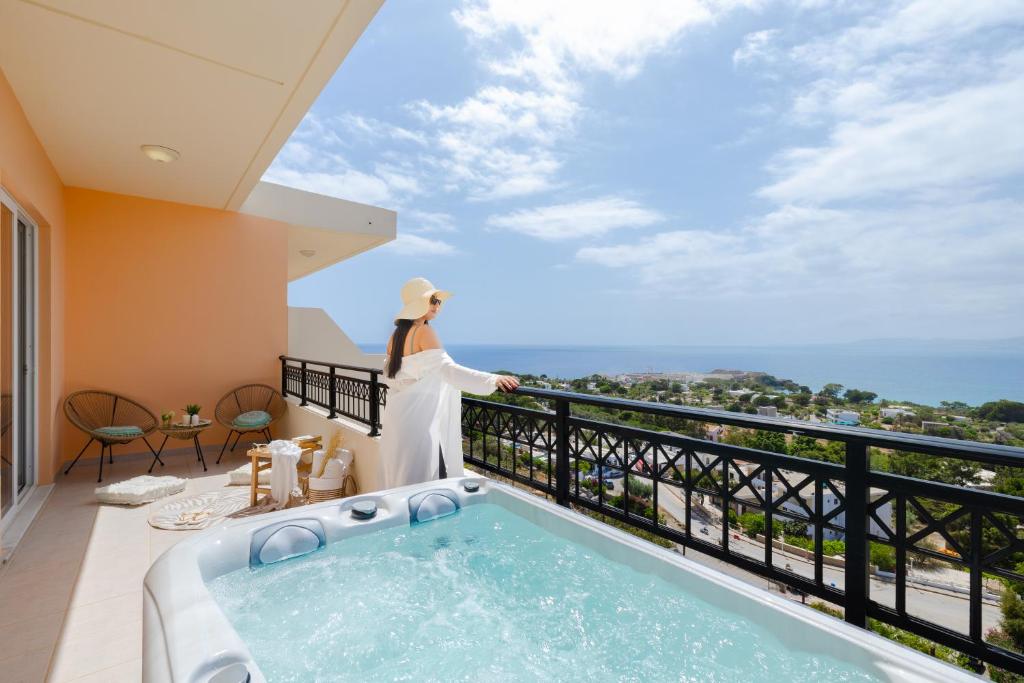a woman standing on a balcony with a hot tub at Hotel Ziakis in Pefki