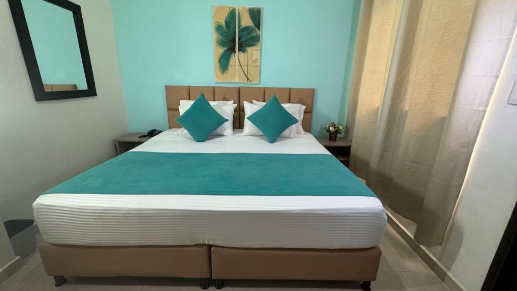 a bedroom with a bed with a green and white comforter at HOTEL CATALUÑA - SOLUCIONES HOTELERAs in Pereira