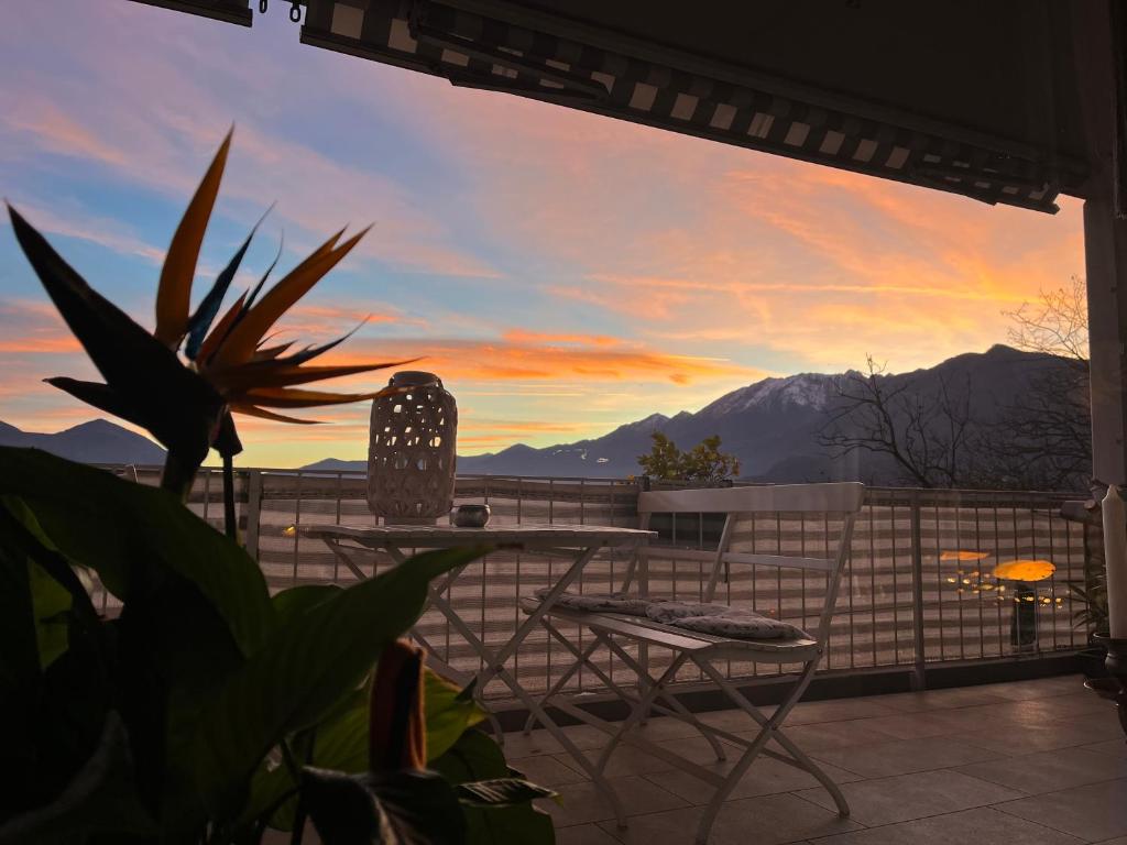 eine Terrasse mit einem Tisch und Stühlen sowie einem Sonnenuntergang in der Unterkunft Paradiso in Locarno
