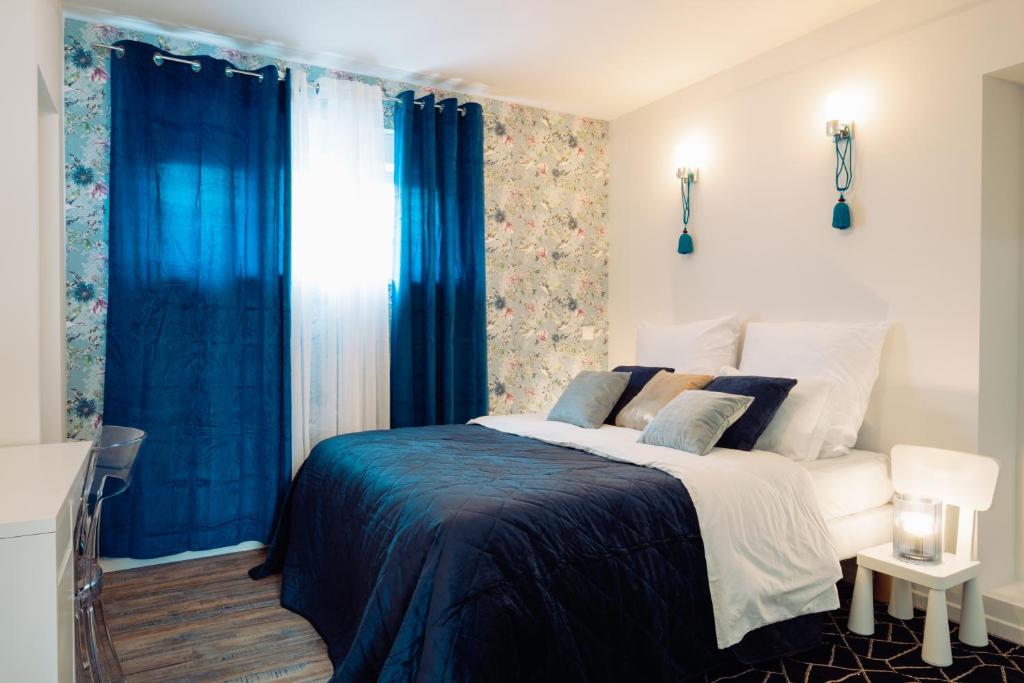 Schlafzimmer mit einem großen Bett und blauen Vorhängen in der Unterkunft Escale Marine Basel Airport in Hésingue