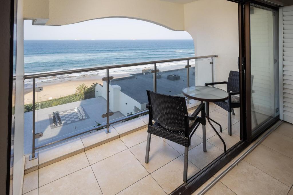 a balcony with a table and chairs and the ocean at 504 Bermudas - by Stay in Umhlanga in Durban