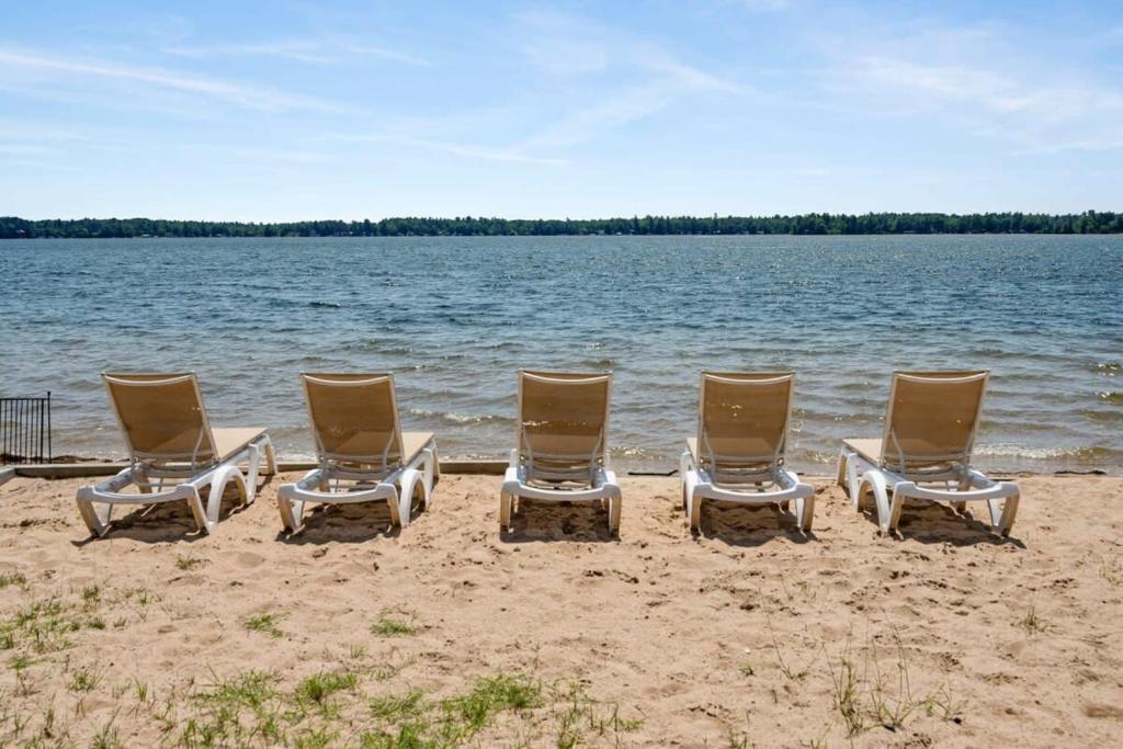a group of chairs sitting on a beach near the water at Fife Lake Lodge 2BR Loft with Kitchen & Lake Views in Fife Lake