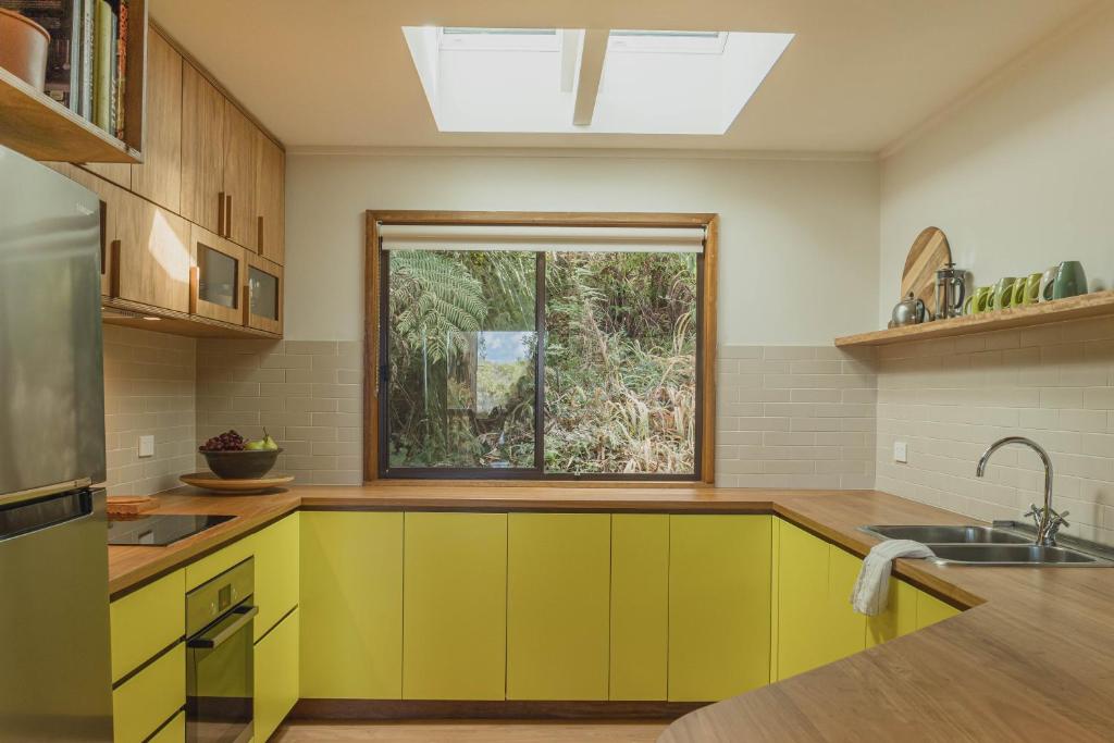 una cocina con armarios amarillos y una ventana en Fern House, en Wye River