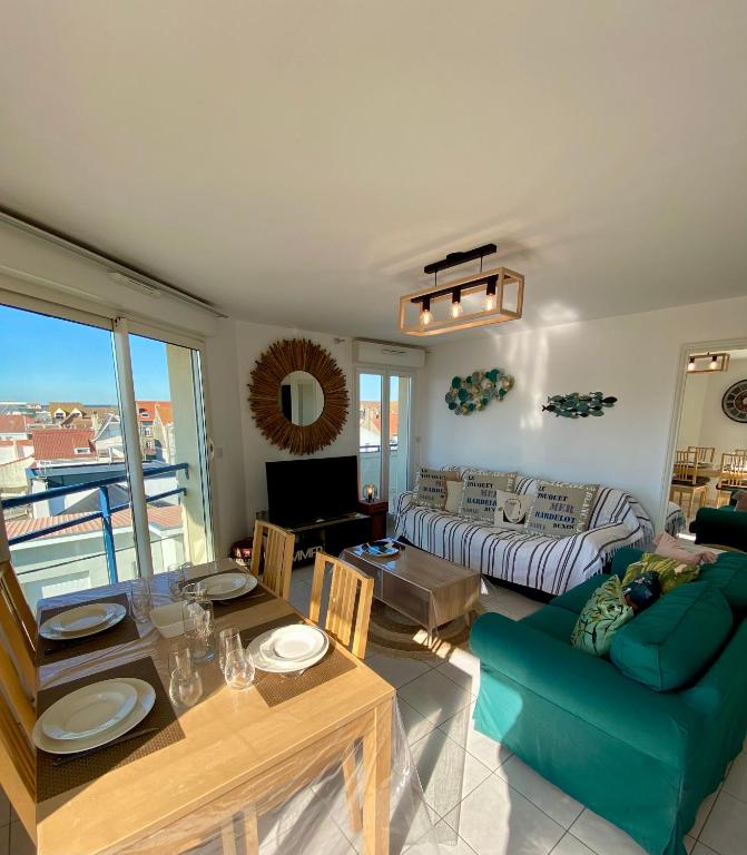 un salon avec une table et un canapé bleu dans l'établissement Opale beach, Merlimont,100msea,2 bedrooms, parking, à Merlimont