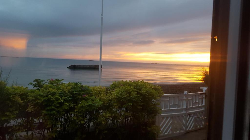 d'un balcon offrant une vue sur l'océan au coucher du soleil. dans l'établissement La bicheraie, à Arromanches-les-Bains