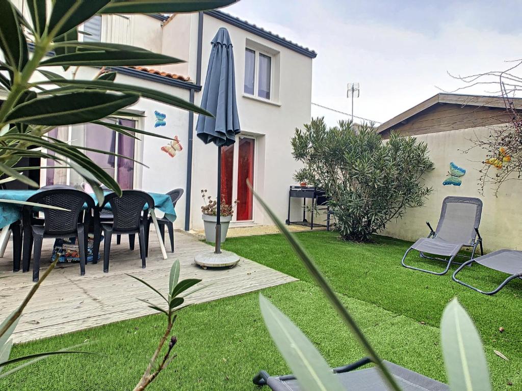 un patio avec des chaises, une table et un parasol dans l'établissement Le clos de Salles, à Salles-sur-Mer