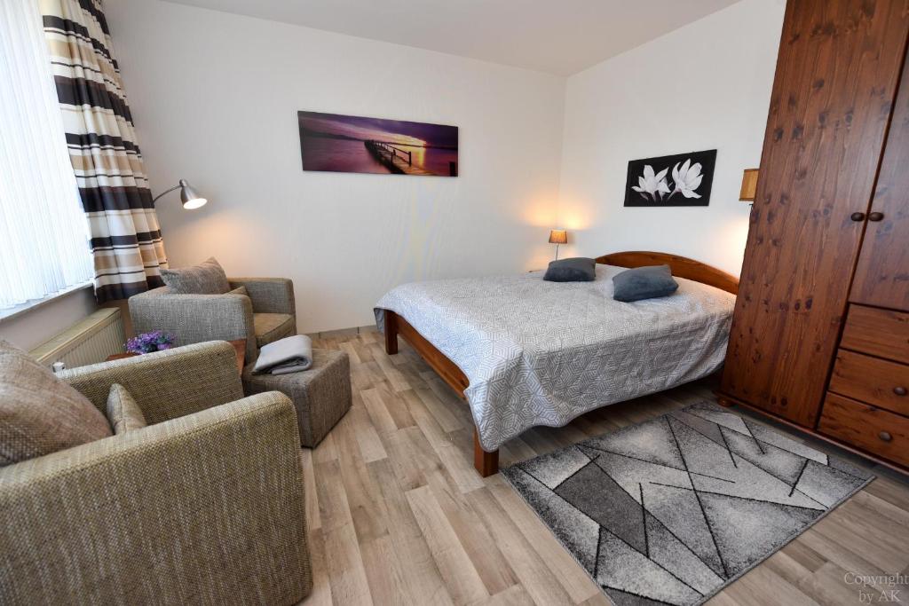 een slaapkamer met een bed, een stoel en een bank bij Haus "Luv und Lee" Appartement LEE15 in Döse