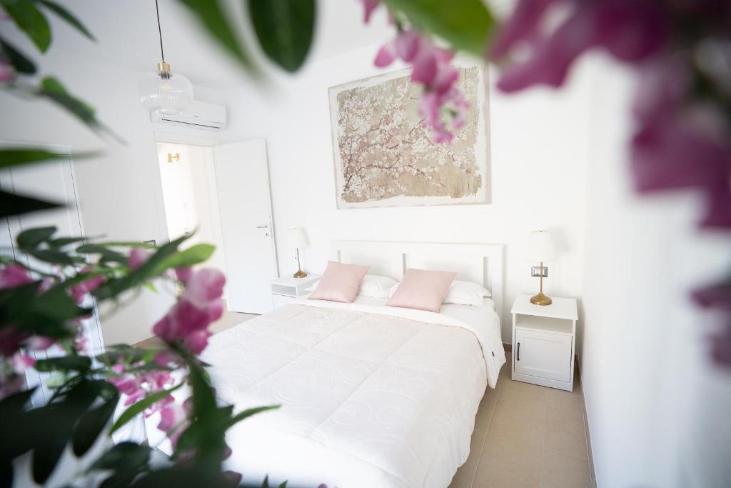 Dormitorio blanco con cama blanca y almohadas rosas en AirPort NOA Modern Home en Fiumicino