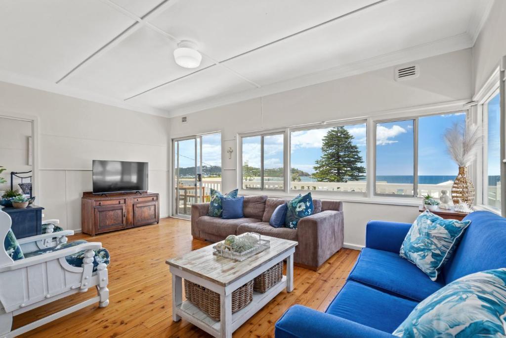 a living room with blue furniture and windows at Delightful 3-Bed Home Minutes from Avoca Beach in Avoca Beach