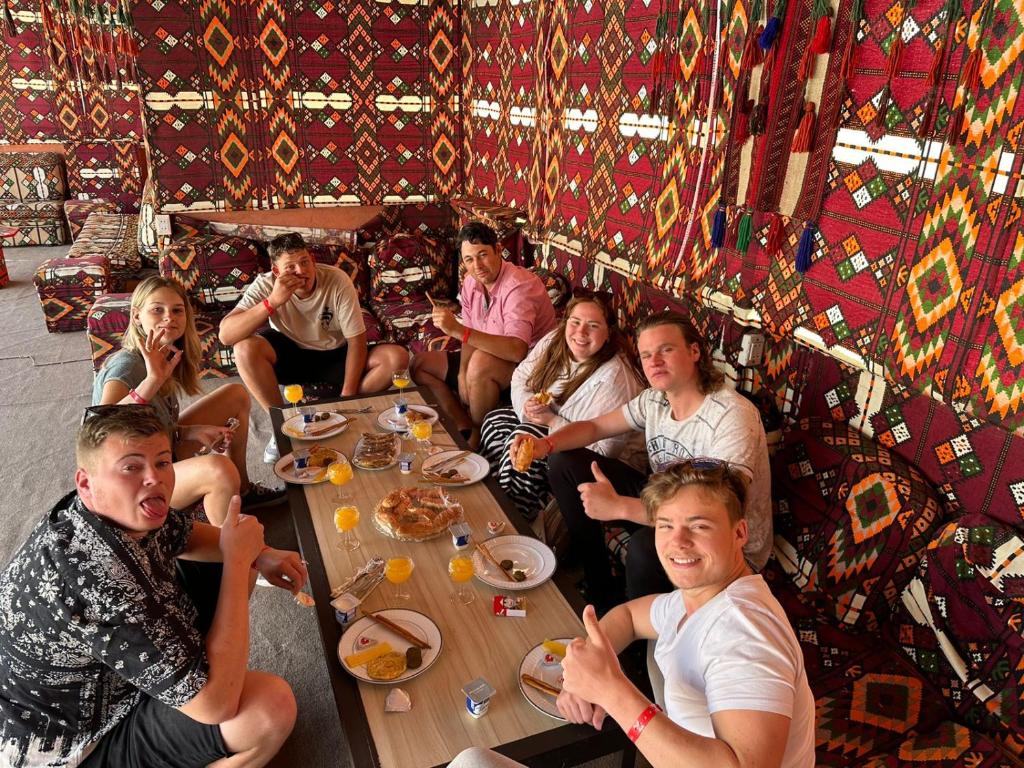 een groep mensen die rond een tafel zitten te eten bij El Khalil Pyramids Inn in Caïro