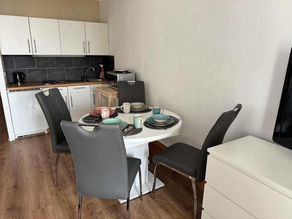 Il comprend une petite cuisine avec une table et des chaises blanches. dans l'établissement Ferienwohnung Emilia - Ruheoase und Entspannung, à Sankt Englmar