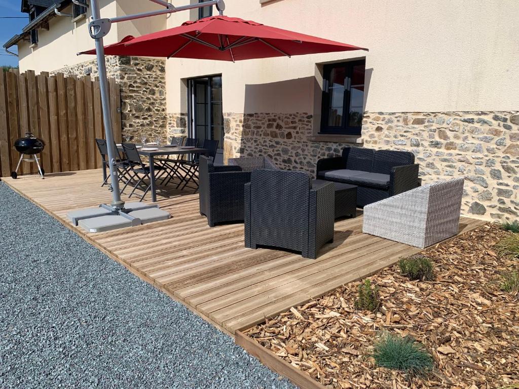 eine Terrasse mit einem Tisch, Stühlen und einem Sonnenschirm in der Unterkunft COTTAGES LA CHENERIE in Ancteville