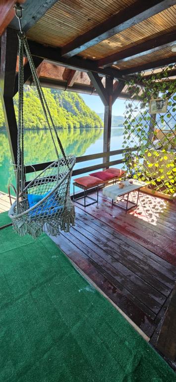 a porch with a hammock and a view of the water at Hogar Splav Perucac in Perućac