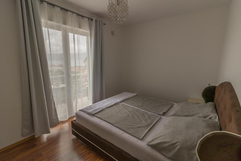 a bedroom with a bed and a large window at Apartmani Vesić in Tivat