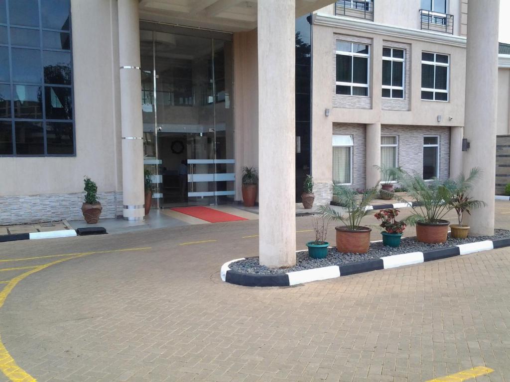 a building with a column and potted plants in front of it at Three Steers Hotel in Meru
