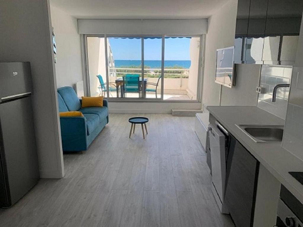 sala de estar con sofá azul y mesa en Vittoria Immobilier-375-Vue mer- REGLEMENT SUR PLACE -Chèques Vacances acceptés, en La Grande-Motte