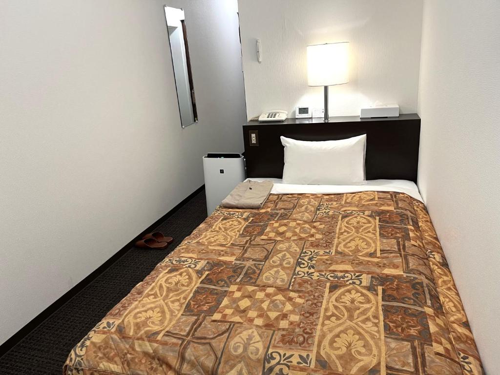 een hotelkamer met een bed met een quilt bij Hotel Tokeidai in Sapporo