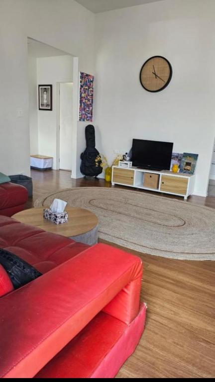 sala de estar con sofá rojo y mesa en Rare GEM in Westgate en Auckland