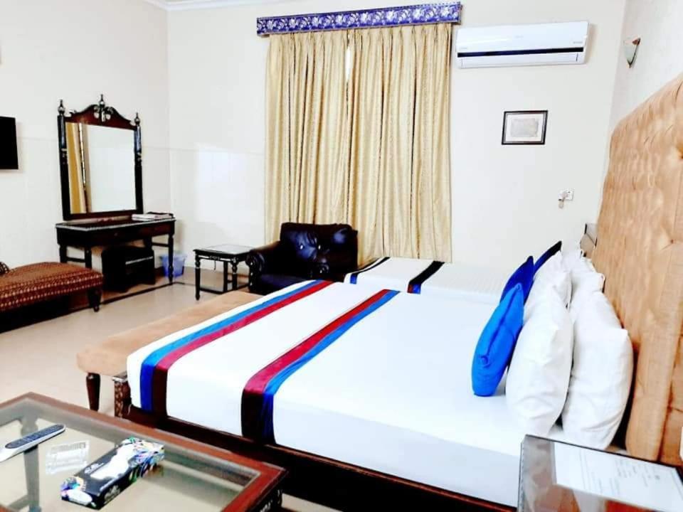 um quarto de hotel com uma cama grande e um espelho em Calming Residence em Lahore