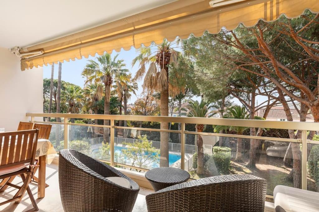 un balcon avec vue sur une piscine et des palmiers dans l'établissement Appartement vue piscine, proche mer, à Vallauris