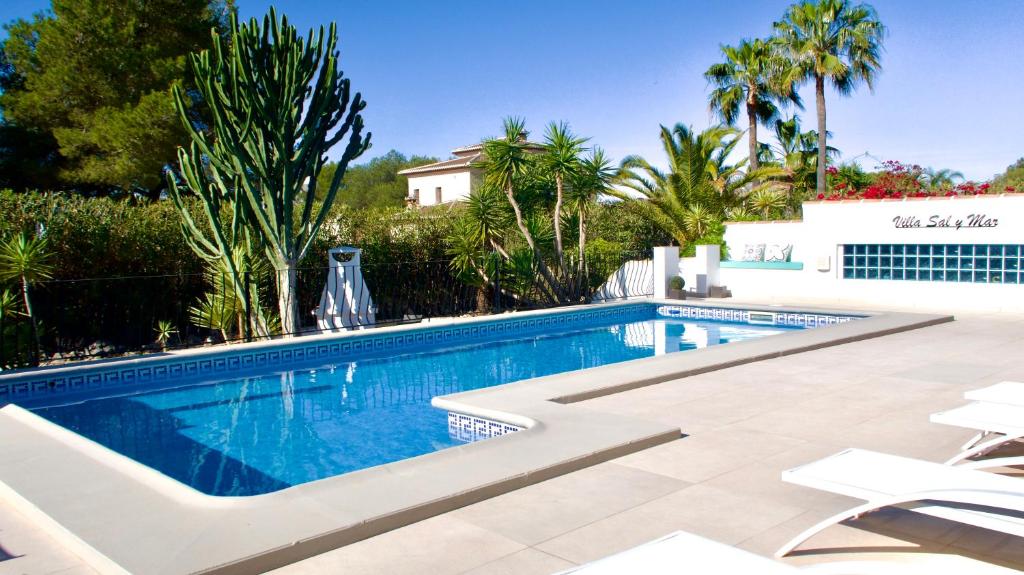 ein Pool mit Stühlen und Bäumen sowie ein Gebäude in der Unterkunft Villa Sal y Mar - Jávea ! Freshly Renovated ! in Jávea