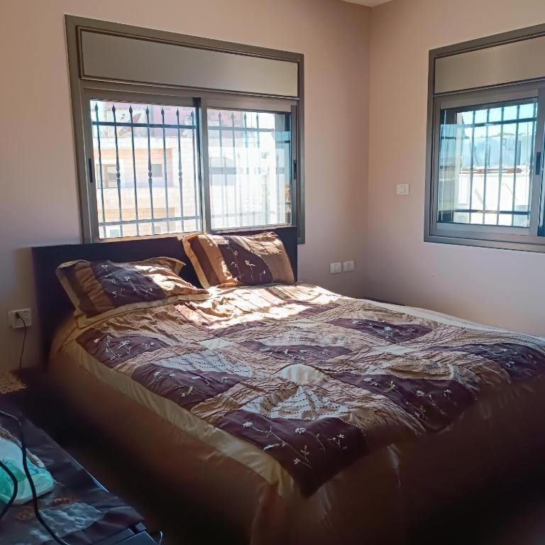 uma cama grande num quarto com duas janelas em Abram's appartment in the Center of Bethlehem city em Belém