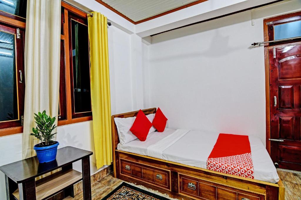um quarto com uma cama com almofadas vermelhas e uma mesa em OYO Flagship Narangam Homestay em Darjeeling