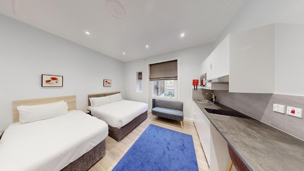 Cette chambre comprend deux lits et un bureau. dans l'établissement MSK Premium, à Londres