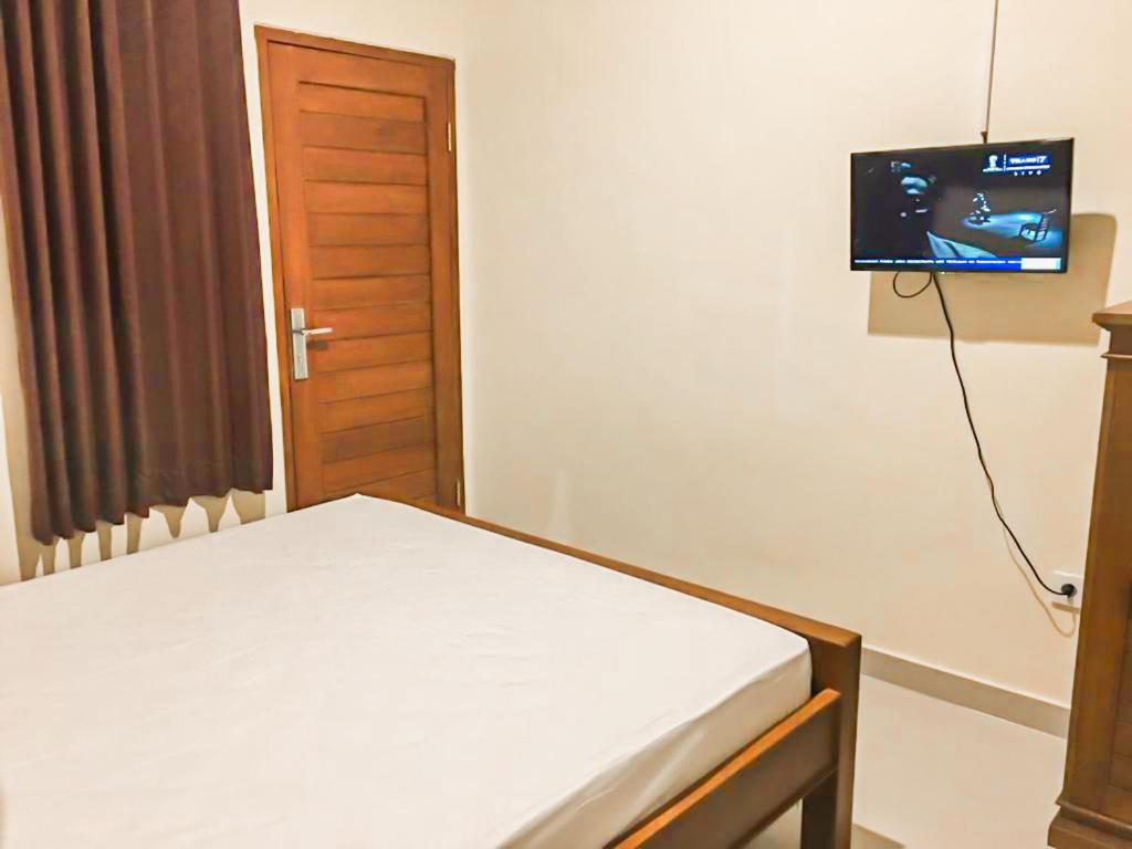a bedroom with a bed and a flat screen tv at Pondok Puvi-Puvi in Ujung