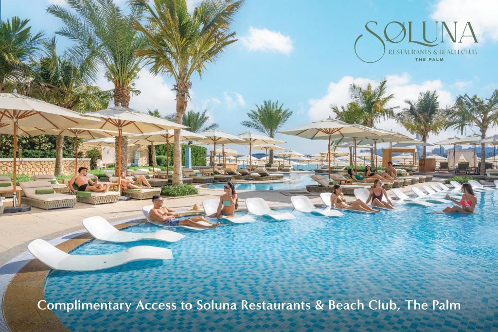 eine Gruppe von Menschen, die in einem Pool in einem Resort sitzen in der Unterkunft The First Collection Business Bay in Dubai