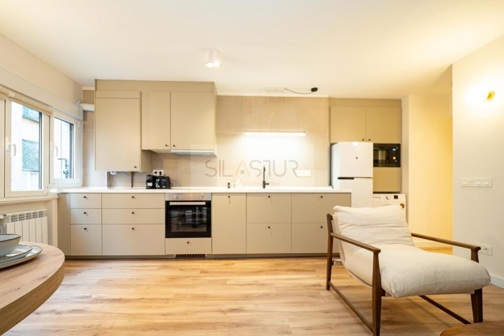 a kitchen with white cabinets and a table and a chair at Sella Apartamento in Gijón