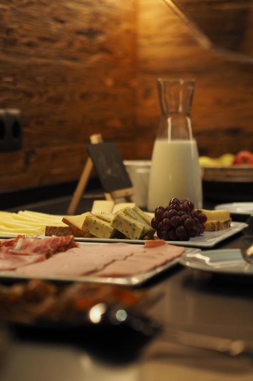 a table with cheese and grapes and a plate of food at Sporthotel Igls in Innsbruck