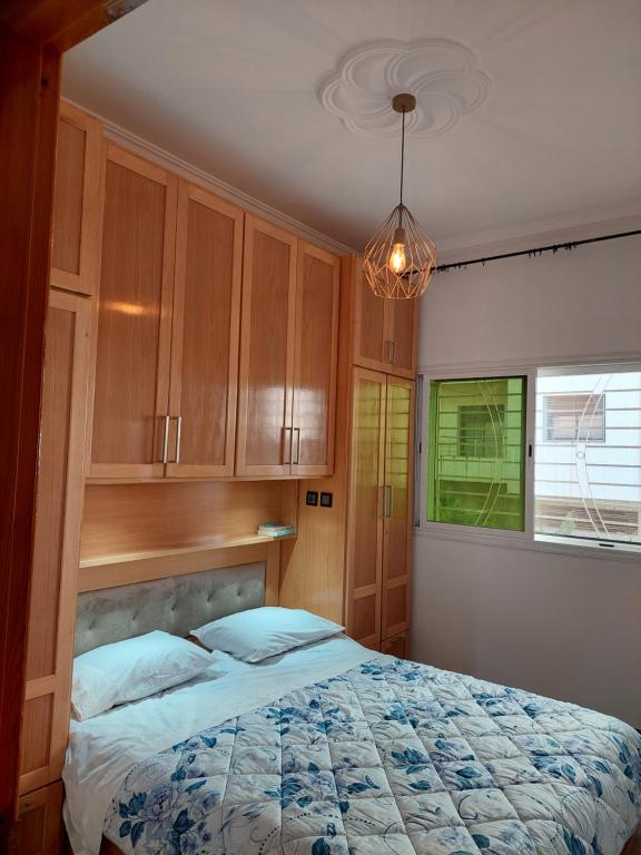 1 dormitorio con cama, ventana y lámpara de araña en Hi Home, en Meknès