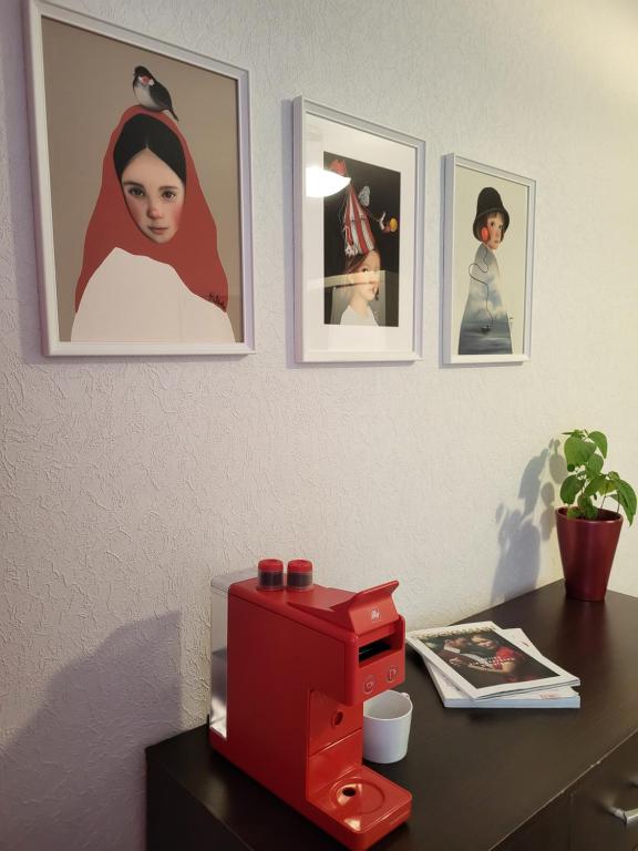 un microondas rojo sobre una mesa con cuadros en la pared en Iļģuciema Apartment, en Riga