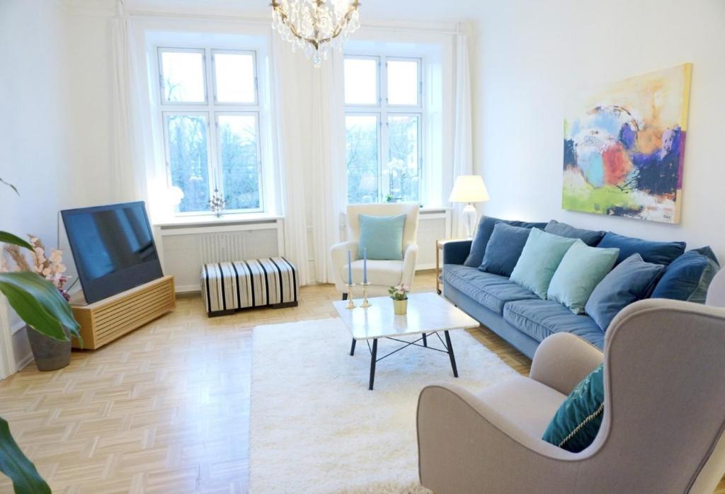 uma sala de estar com um sofá azul e uma televisão em Serviced Luxury Apartment in Østerbro - incl housekeeping once a week em Copenhague