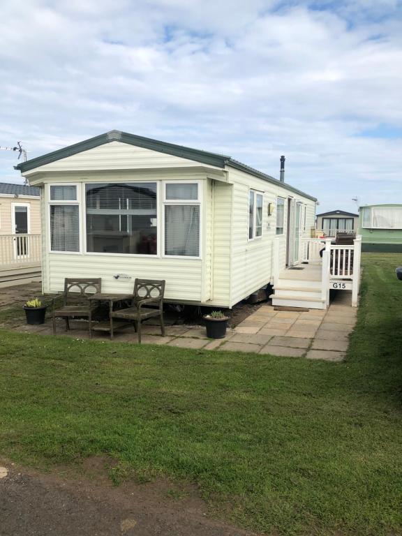 una caravana blanca con una mesa y un banco en un patio en Eyemouth getaway, en Eyemouth