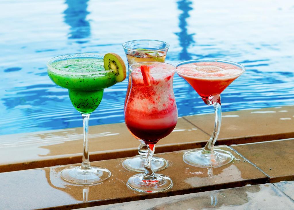 three cocktails sitting on a table next to a pool at Centro Al Manhal by Rotana in Abu Dhabi