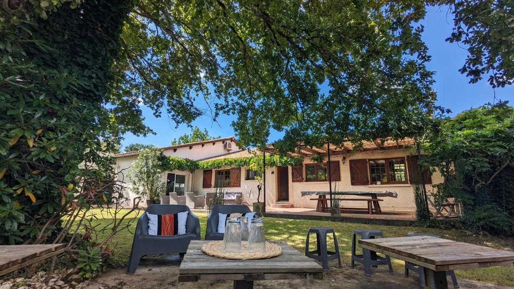 - une table de pique-nique et des chaises en face d'une maison dans l'établissement Bordeaux Océan Médoc Maison de charme classée 4 étoiles, à Parempuyre