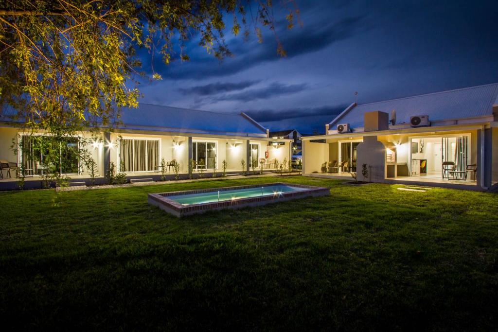 une maison avec une piscine dans la cour la nuit dans l'établissement El Dorado Hotel and Self Catering, à Oudtshoorn