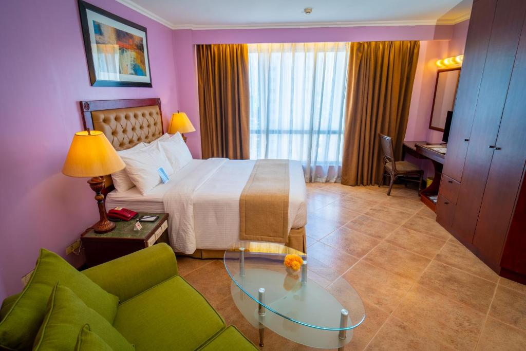 Habitación de hotel con cama y sofá verde en Royal Bellagio Hotel, en Manila